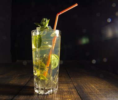 Siyah arka planda cam bir tankta naneli ve buzlu mojito kokteyli. Soğuk yaz içeceği ve kokteyl