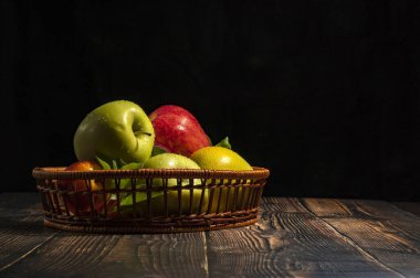 Çiy içindeki bir sepet taze elma, arka plandaki ahşap bir masaya düşer..
