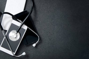 Akıllı telefonlar ve masanın üstüne bir stetoskop.