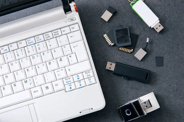 Weißer Laptop mit verschiedenen Datenträgern — Stockfoto