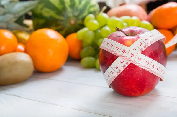 Apfel und Maßband vor fruchtigem Hintergrund — Stockfoto