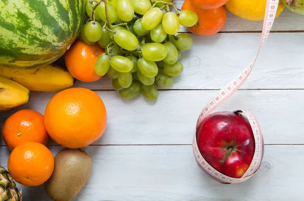 Manzana y cinta métrica con frutas sobre tabla de madera —  Fotos de Stock