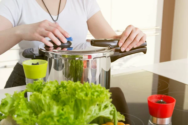 Mulher usa panela de pressão para cozinhar uma refeição . — Fotografia de Stock