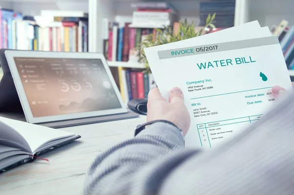 Man holds invoice of water usage — Stock Photo, Image