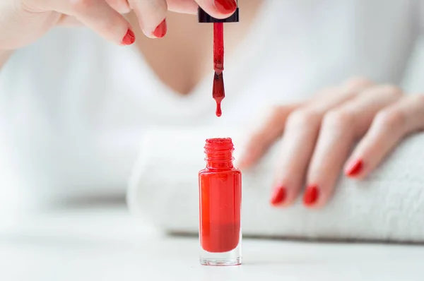 Primer plano de esmalte de uñas rojo gota wih mujer uñas en backbround — Foto de Stock