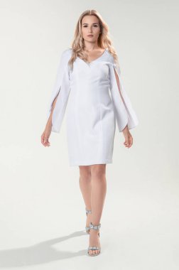 Beyaz arka plan üzerinde beyaz şık elbiseli genç sarışın