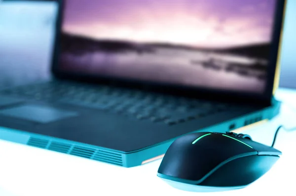 Modern glowing mouse connected to gaming laptop