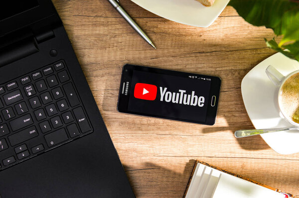 Samsung A5 is laying on the desk with YouTube logo on screen.