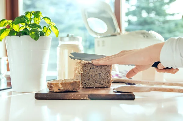 Mano da donna con coltello da cucina tagliando pane sano fatto in casa — Foto Stock