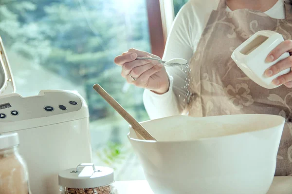 Женщина наливает соль в тесто для домашнего хлеба — стоковое фото