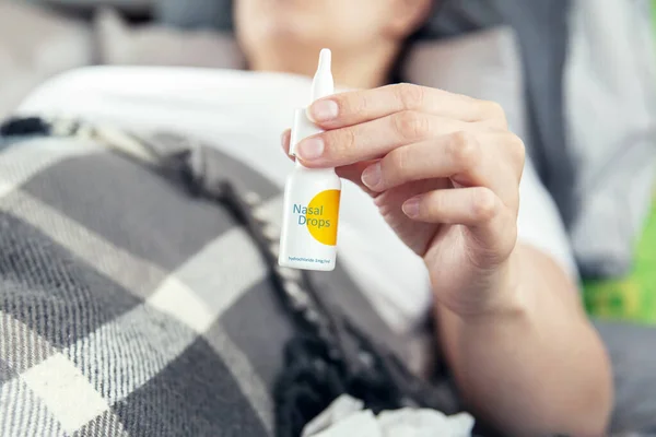 Ill Woman Lies Bed Covered Blanket Holds Nasal Drops Hand — Stock Photo, Image