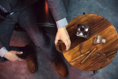 Beyefendi bir bardak viski ve bir sürahi viski ve puroyla dolu ahşap bir masa alır. Yukarıdan görüntüle.
