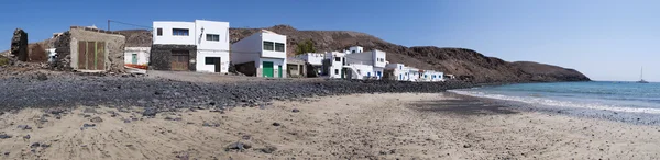 Fuerteventura, Canary Islands, Spain: the black beach and white houses of Pozo Negro, a fishing village away from touristic places whose black beach was created by lava flows millions years ago — Stock Photo, Image