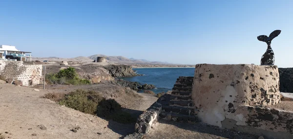 Fuerteventura, Ilhas Canárias, Espanha: vista aérea do penhasco com o Castillo de el Toston (Torre ou Castelo de Toston) na aldeia de El Cotillo, e uma escultura de cauda de baleia no porto — Fotografia de Stock