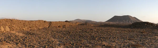 Fuerteventura, Kanárské ostrovy, Španělsko: panoramatický pohled při západu slunce kamenné zdi a pohoří na polní cestě z malé rybářské vesnice Majanicho na hlavní města Corralejo — Stock fotografie