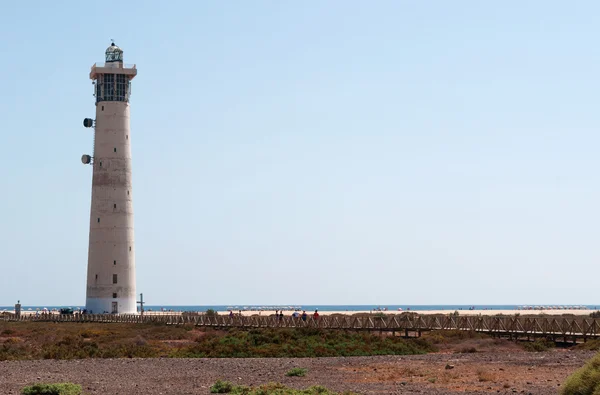 Fuerteventura, Canary Islands, Spain: wooden fence and the Morro Jable Lighthouse (Faro de Morro Jable), the tallest lighthouse of Canaries, opened in 1991 at the edge of the beach near Morro Jable, the southernmost town of the island — Stock Photo, Image