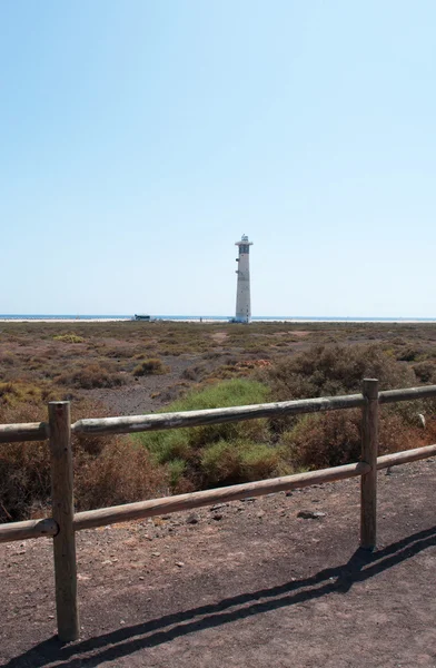 Fuerteventura, Canary Islands, Spain: wooden fence and the Morro Jable Lighthouse (Faro de Morro Jable), the tallest lighthouse of Canaries, opened in 1991 at the edge of the beach near Morro Jable, the southernmost town of the island — Stock Photo, Image