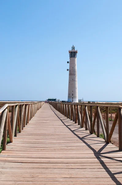 Fuerteventura, Ilhas Canárias, Espanha: cerca de madeira e o Farol Morro Jable (Faro de Morro Jable), o farol mais alto de Canárias, inaugurado em 1991 à beira da praia perto de Morro Jable, a cidade mais meridional da ilha — Fotografia de Stock