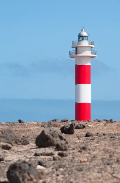 Fuerteventura, Islas Canarias, España: rocas negras y vista del Faro de Toston (faro de Toston o faro de El Cotillo), un faro activo en Punta de la Ballena cuya estructura original fue inaugurada en 1897 — Foto de Stock