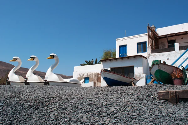 Fuerteventura, Canarische eilanden, Spanje: zwaan-vormige pedaal boten op het zwarte strand van Pozo Negro, een vissersdorp uit de buurt van toeristische plaatsen waarvan zwarte strand was gemaakt door lava stroomt miljoenen jaren geleden — Stockfoto
