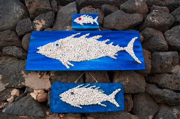 Painéis de madeira com peixes pendurados em rochas pretas — Fotografia de Stock