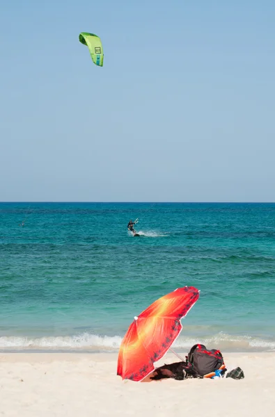 Fuerteventura, Islas Canarias, España: kitesurf y sombrilla en la playa de Grandes Playas, una de las famosas playas de kitesurf y windsurf, con vistas a la isla de Lobos, pequeña isla a 2 km al norte de Fuerteventura — Foto de Stock