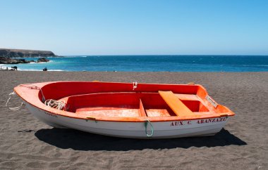 Fuerteventura, Kanarya Adaları, İspanya: görünümünü Ajuy siyah plaj renkli bir teknede, onun mağaralar için ünlü adanın batı kıyısında balıkçı köyü