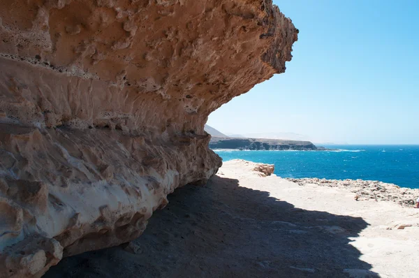 Fuerteventura, Islas Canarias, España: rocas y arena en el sendero a las cuevas de Ajuy, el pueblo pesquero en la costa occidental de la isla famosa por sus cuevas, su playa negra y los coloridos barcos — Foto de Stock