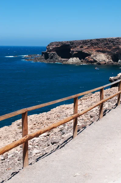 Fuerteventura, Islas Canarias, España: el sendero sobre un acantilado que conduce a las cuevas de Ajuy, el pueblo pesquero en la costa occidental de la isla famosa por sus cuevas, su playa negra y los coloridos barcos — Foto de Stock