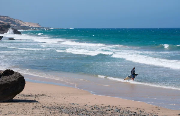 Фуэртевентура, Канарские острова, Испания: серфер на Playa de Garbel, черном пляже, известном среди серферов своими волнами, на западном побережье острова, где лежит обломки корабля American Star, затонувшего в 1994 году — стоковое фото