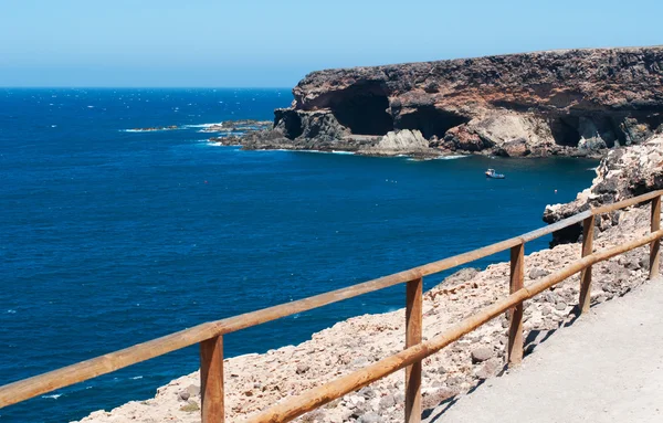 Fuerteventura, Islas Canarias, España: el sendero sobre un acantilado que conduce a las cuevas de Ajuy, el pueblo pesquero en la costa occidental de la isla famosa por sus cuevas, su playa negra y los coloridos barcos — Foto de Stock