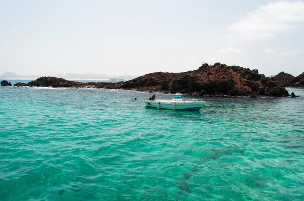 Fuerteventura, Kanári-szigetek, Spanyolország: kristálytiszta víz az Atlanti-óceán és a hajó látható a kis mólón a Lobos-szigetre (Islote de Lobos), egy kis szigeten mindössze 2 km-re északra található Fuerteventura szigetén — Stock Fotó