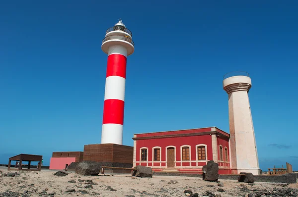 Fuerteventura, Islas Canarias, España: rocas negras y vista del Faro de Toston (faro de Toston o faro de El Cotillo), un faro activo en Punta de la Ballena cuya estructura original fue inaugurada en 1897 — Foto de Stock