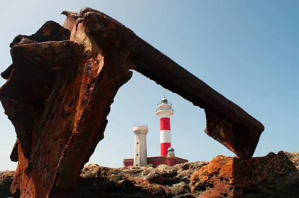 Fuerteventura, Islas Canarias, España: rocas negras con Faro de Toston (faro de Toston o faro de El Cotillo), un faro activo en Punta de la Ballena abierto en 1897, visto a través de los restos oxidados del naufragio de un barco — Foto de Stock