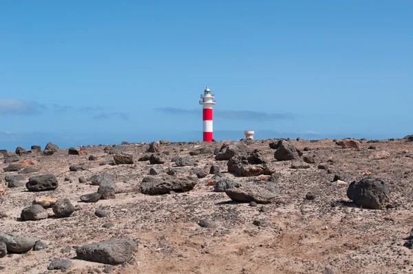 Fuerteventura, Canary Islands, Spain: black rocks with Faro de Toston (Toston lighthouse or El Cotillo lighthouse), an active lighthouse at Punta de la Ballena (Whale Point) whose original structure was opened in 1897 — Stock Photo, Image