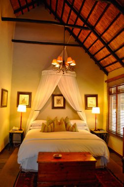 Safari in South Africa: a romantic bedroom at the Ngala Private Game Reserve, a luxury safari lodge located in the Kruger National Park, one of the largest game reserves in Africa since 1898, South Africa's first national park in 1926 clipart