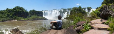 Iguazu, 13/11/2010: buzlu Iguazu Falls, Latin Amerika'nın en önemli turistik önünde oturan bir adam