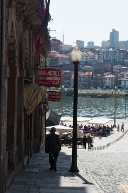 Porto: bir sokak lambası ve merkezi Praça da Ribeira Nehri, Meydanı eski şehrin el sanatları dükkan işaretleri manzaralı doğru yürüyen yaşlı bir adam