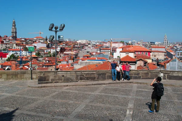 Porto: um homem a fotografar um grupo de turistas com telhados vermelhos, o horizonte da Cidade Velha e a Torre dos Clerigos, uma torre de pedra em estilo barroco construída entre 1754 e 1763 — Fotografia de Stock