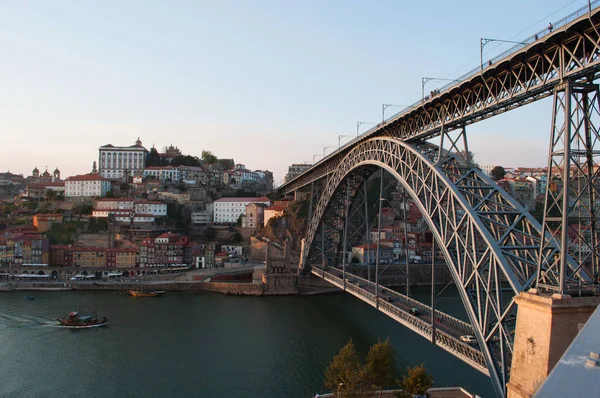 Португалия: лодки на закате и панорама Порту с видом на Луиз I, двойной металлический арочный мост на реке Доуро между Порту и Вила-Нова-де-Гайа — стоковое фото