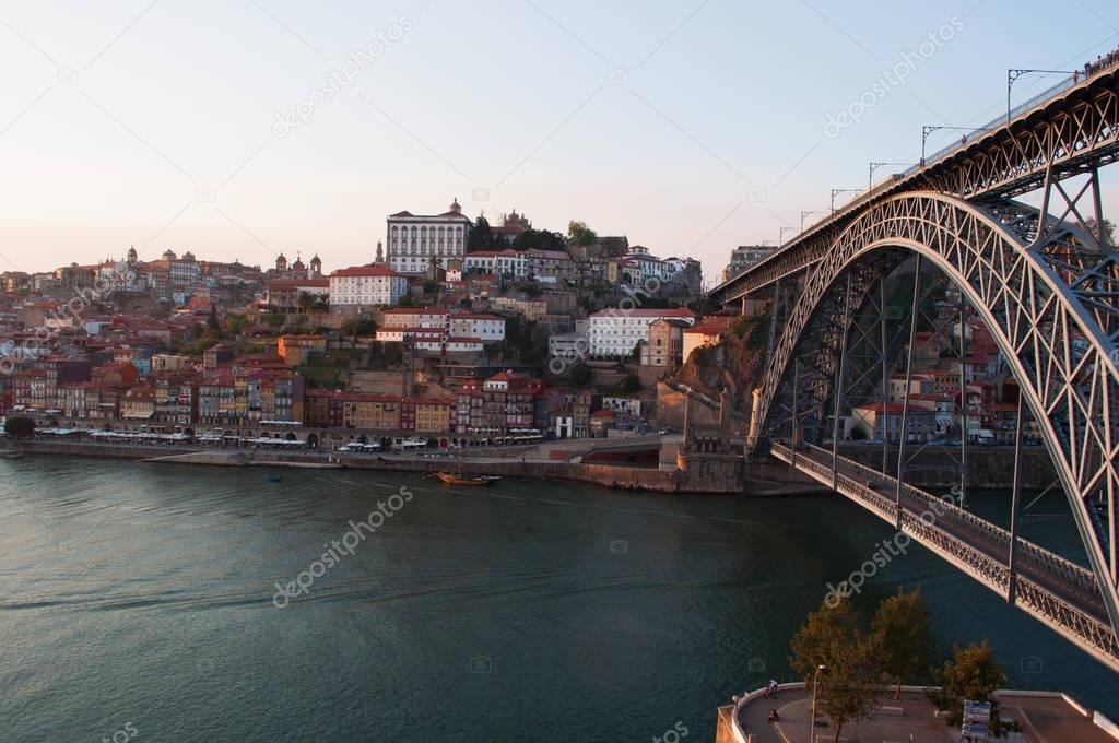 Portugal: boats at sunset and the skyline of Porto with view of the Luiz I, the double-decked metal arch bridge on the Douro River between Porto and Vila Nova de Gaia