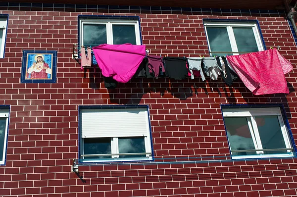 Basque Country, Spain: red building with votive ceramic tiles and windows with laundry hanging to dry in the Old City of Donostia San Sebastian, the coastal city on the Bay of Biscay — Stock Photo, Image