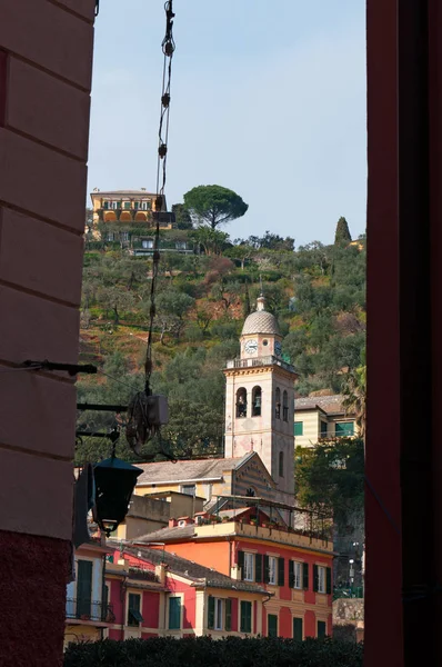 Portofino: een steegje met uitzicht op de klokkentoren van het 12e-eeuwse kerk van St. Martin, Divo Martino, de gestreepte kerk gewijd aan Sint-Maarten van Tours in de oudste wijk van de buitenwijk — Stockfoto