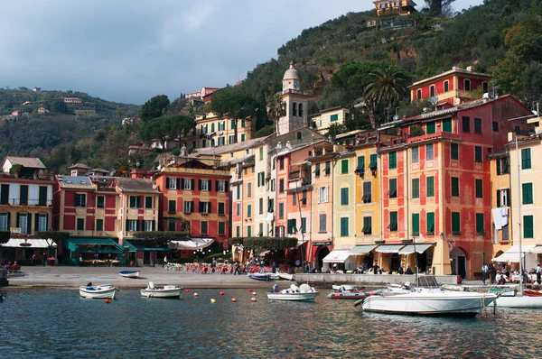 Италия: вид на город и вид на рыбацкие лодки в порту Портофино, итальянская рыбацкая деревня, известная своей живописной гаванью, бухтой и красочными домами — стоковое фото