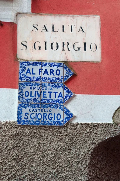 Italien: keramiska skyltar till fyren, Olivetta stranden och slottet St. George, några av de största attraktionerna i Portofino, en berömd italiensk fiskeby i nordöstra Italien — Stockfoto