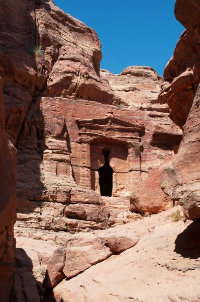 Jordânia, Oriente Médio: vista de um túmulo esculpido na face rochosa da montanha no caminho até o mosteiro na cidade arqueológica de Nabataean Petra — Fotografia de Stock