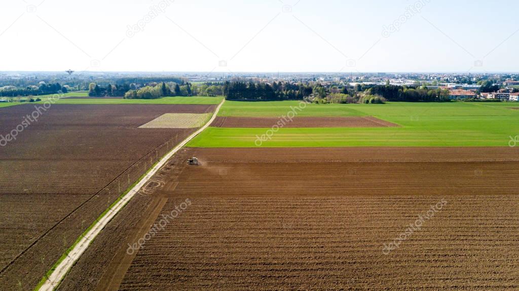 Tractor plowing the fields, aerial view of a plowed field and a tractor that sowing