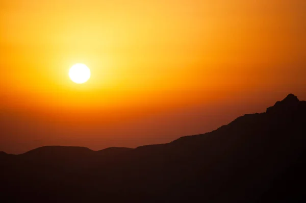 Un coucher de soleil ardent sur le contour sombre d'une montagne — Photo