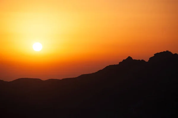 Un coucher de soleil ardent sur le contour sombre d'une montagne — Photo