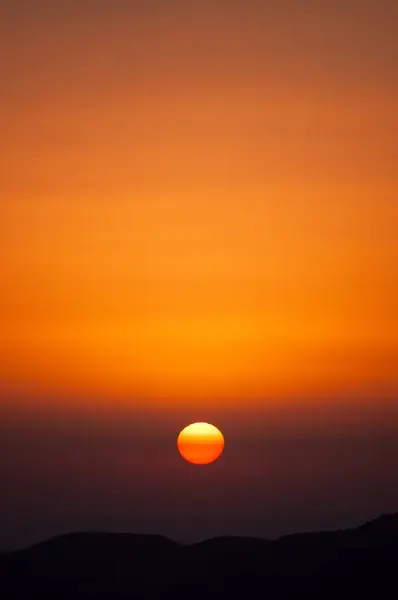 Un coucher de soleil ardent sur le contour sombre d'une montagne — Photo